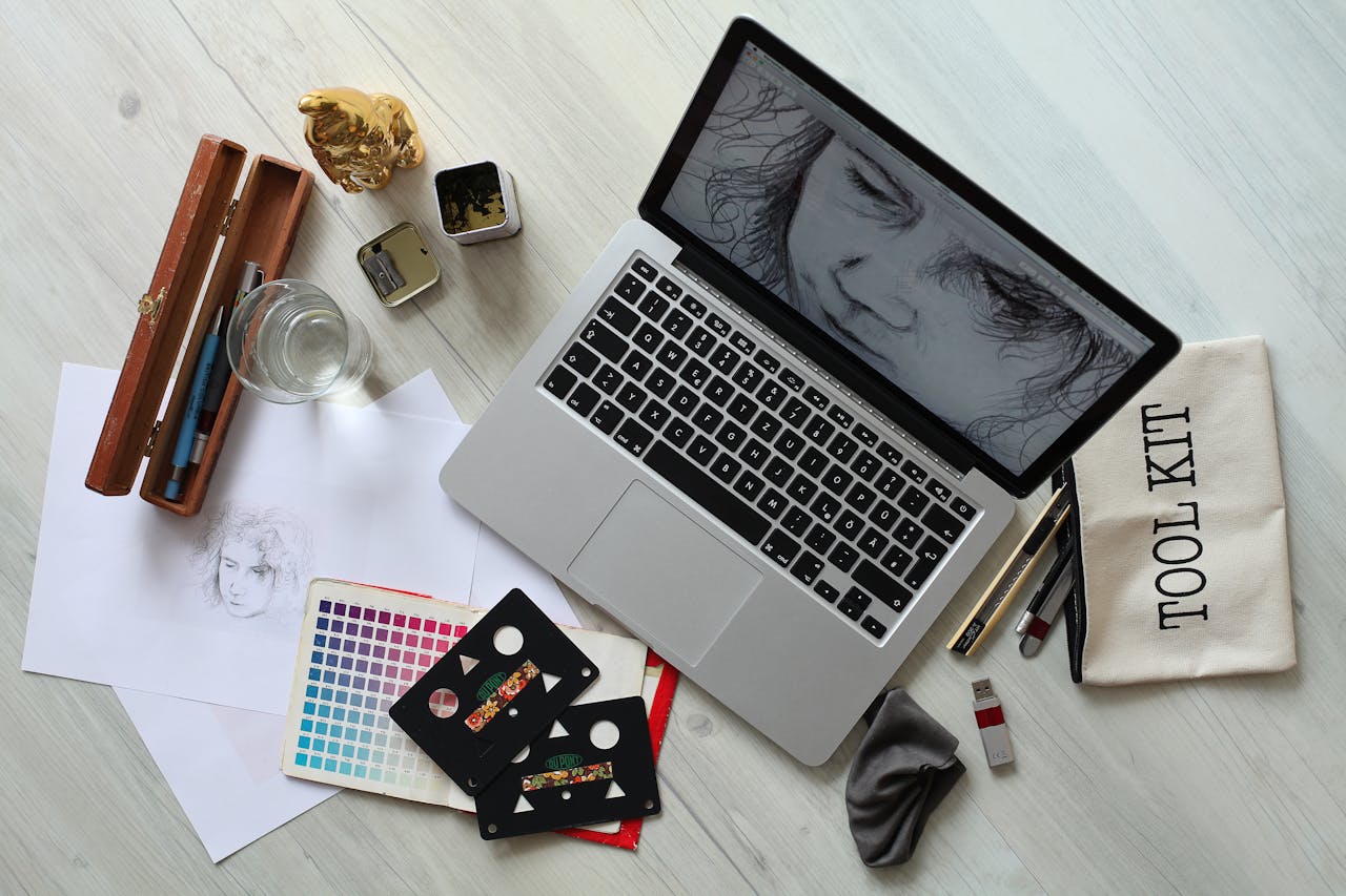 About Top view of a creative workspace with a laptop, sketch supplies, and color palette.